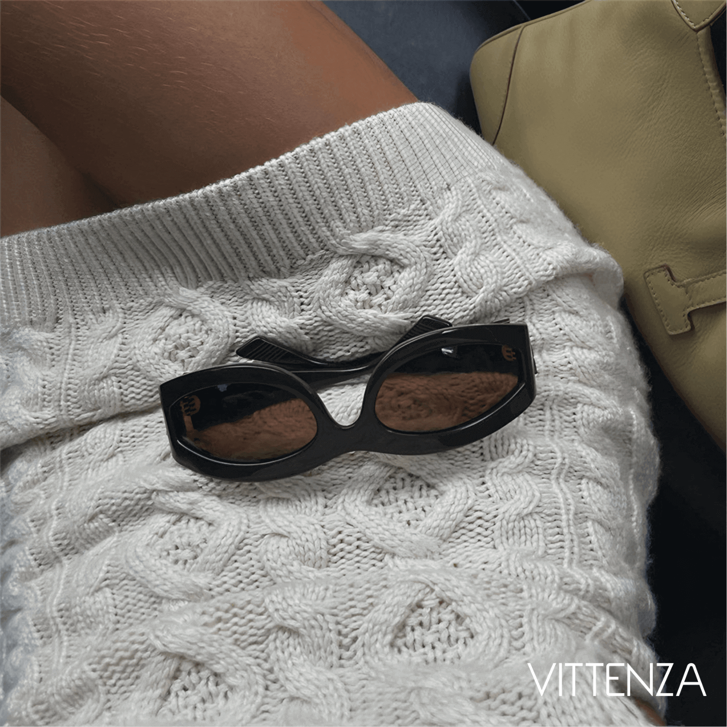 Close-up of the intricate knit texture of the Abrazo dress in nude white with sunglasses detail