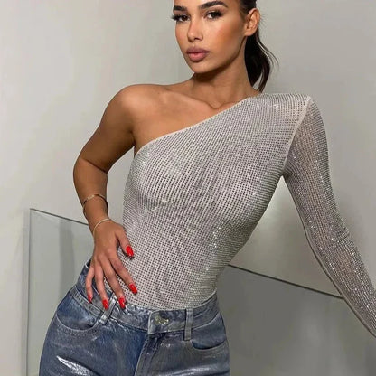 Woman wearing an elegant one-shoulder asymmetric sequin top paired with metallic jeans, showcasing a sophisticated and modern look.