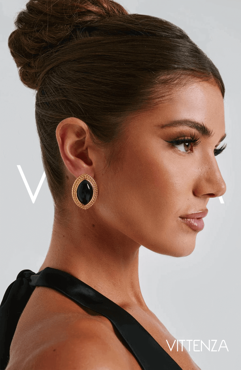 Side view of a model wearing Azra Earrings in black with a textured gold frame, showcasing the refined ellipse design.