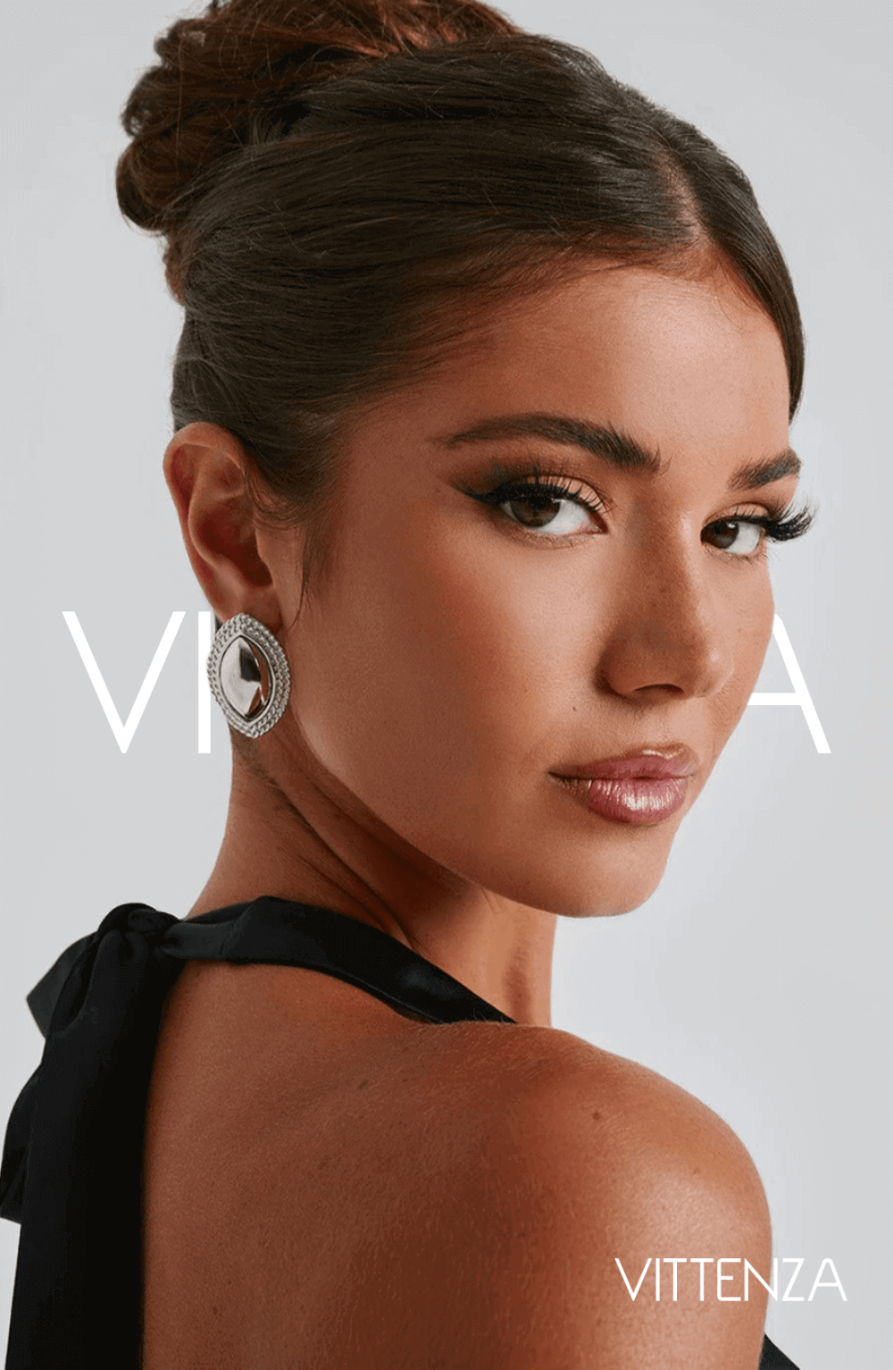 Front view of a model wearing Azra Earrings in silver with a smooth metallic center and textured silver frame, showcasing the modern ellipse design.