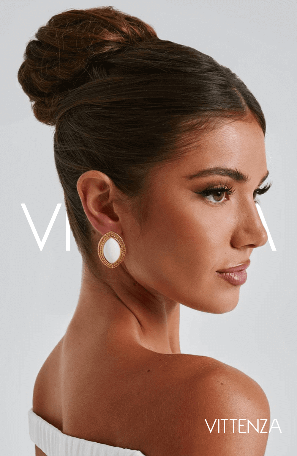 Model wearing Azra Earrings in white with a textured gold frame, highlighting the elegant ellipse design.