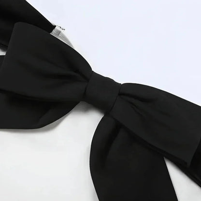 Close-up of the black bow detail on a classic black and white off-shoulder dress.