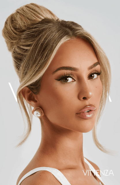 Close-up of a model wearing Davina Earrings in rose gold with a pearl centerpiece and textured frame, styled with a high bun.