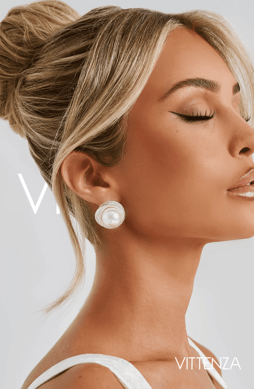 Close-up of a model wearing Davina Earrings in silver with a pearl centerpiece and textured circular frame, styled with a sleek high bun.