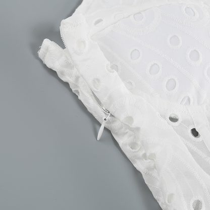 Close-up of the white Bali Dress fabric, highlighting the intricate embroidery and side zipper detail.