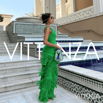 Side view of the green Bahamas dress worn by a model near a decorative pool, highlighting the layered fringe and body-hugging fit.