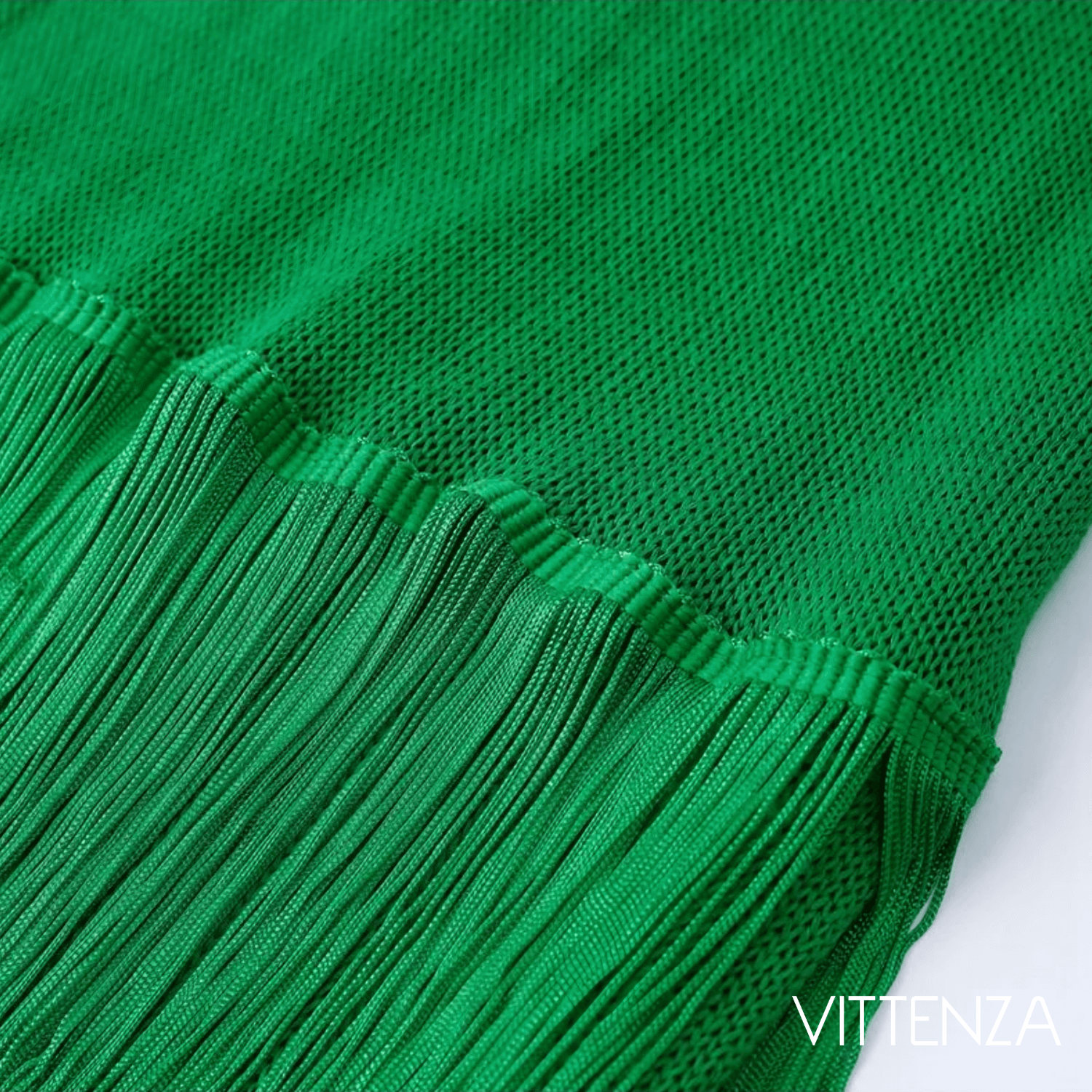 Close-up of the fringed hem of the green Bahamas dress, highlighting the fine knit fabric and fringe details.