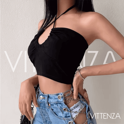 Close-up of a model wearing black halter neck crop top paired with statement chain denim.