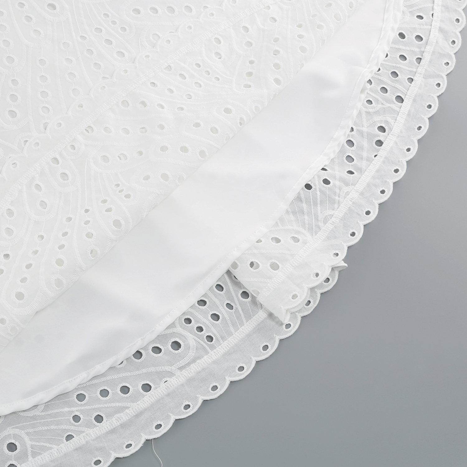 Close-up of the hem of the white Bali Dress, showing the scalloped edge and layered lining.